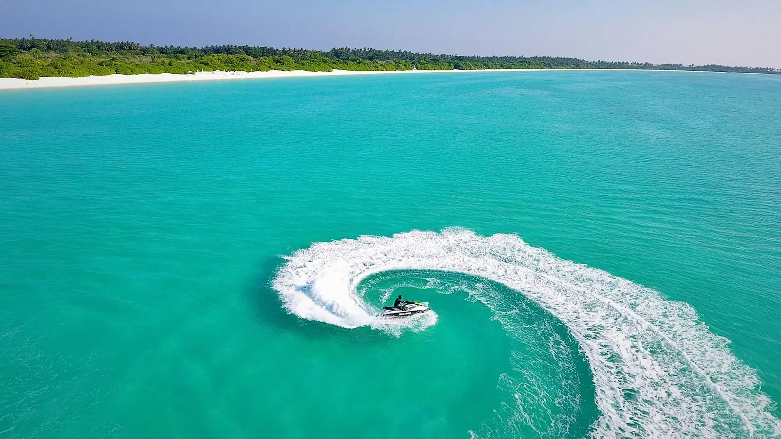 Moto de agua trazando una espiral sobre una laguna turquesa, vista aérea